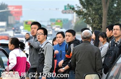 沒擠上的乘客翹首企盼下一輛公交車的到來。