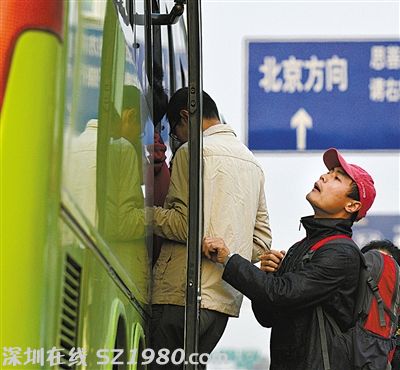 一名乘客在車門口往車?yán)飶埻?，看是否還有空位能擠進去。