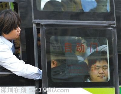 售票員用手將門口的乘客往里推，以便車門能順利關(guān)上。